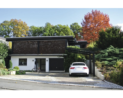 Une maison à deux étages avec une voiture, un vélo et un chemin pavé.
