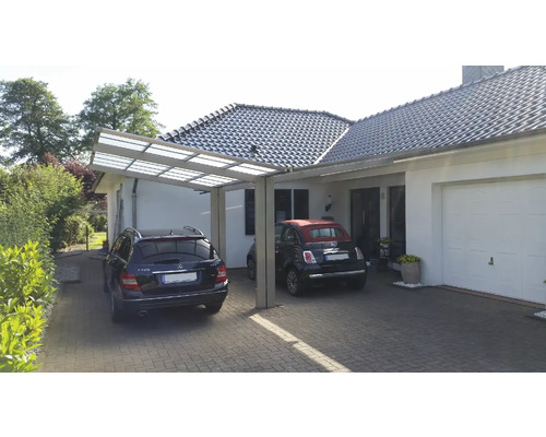 Abri de voiture en métal avec deux voitures devant une maison d''habitation