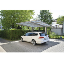 Ein weißes Auto steht unter einem Carport auf einem gepflasterten Parkplatz.