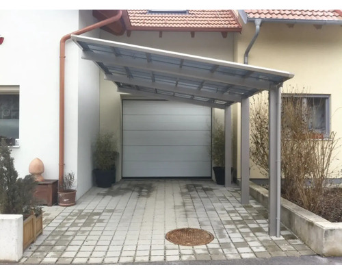 Abri de voiture en métal devant un garage et une maison d''habitation