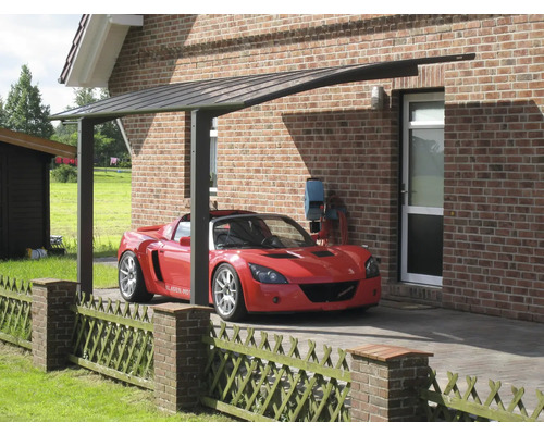 Voiture sous un abri de voiture devant une maison en briques