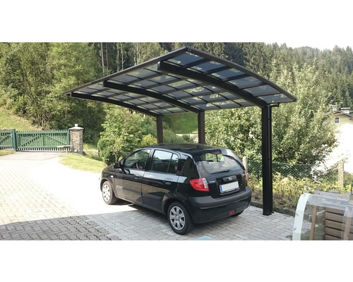 Abri de voiture avec une voiture dans une cour pavée