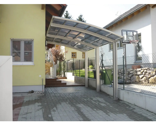 Carport en aluminium avec toit transparent à côté d''une maison d''habitation.