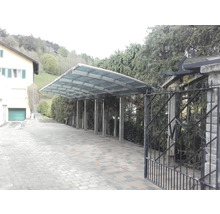 Carport avec structure métallique et toit en verre à côté d''une maison.