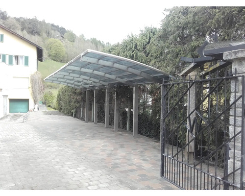 Carport avec structure métallique et toit en verre à côté d''une maison.