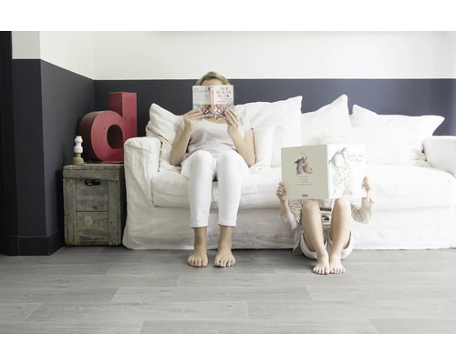 Salon avec canapé blanc, coffre en bois et personnes lisant des livres