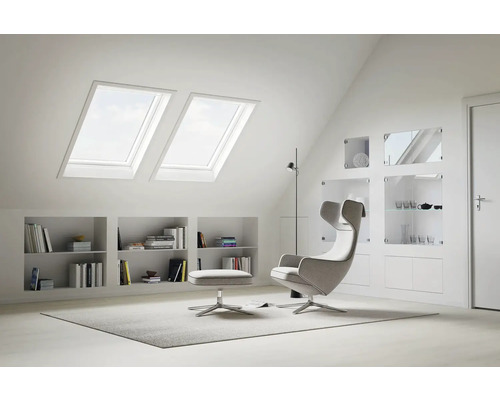 Helles Dachgeschosszimmer mit Dachfenstern, Regalen und modernem Sessel