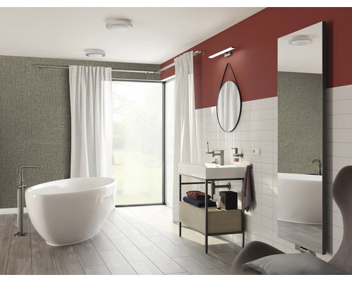 Salle de bain lumineuse avec baignoire, lavabo, miroir et fenêtre pour une ambiance moderne