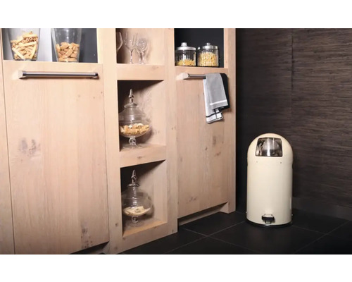 Innenaufnahme eines Raumes mit Holzschrank, Glasbehältern mit Lebensmitteln, Handtuch und Treteimer.