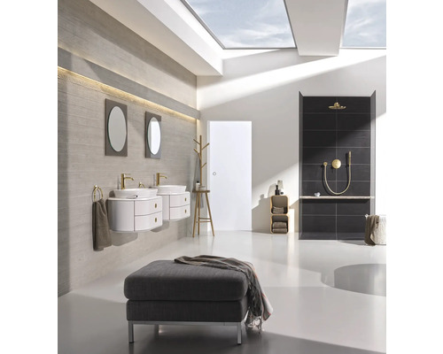 Salle de bains avec lavabos, miroirs, douche et tabouret sous une fenêtre de toit.
