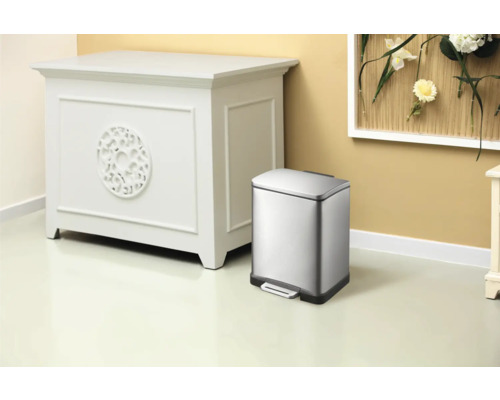 Poubelle en acier inoxydable avec pédale à côté d''une armoire blanche