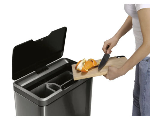 Frau wirft Orangenschalen in einen Mülleimer mit mehreren Fächern