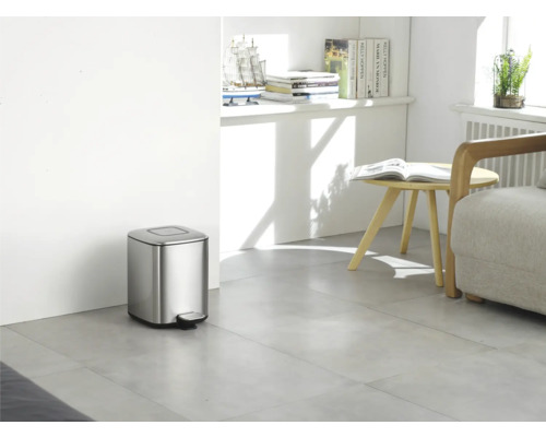 Photo d''intérieur d''une pièce avec une poubelle à pédale en métal argenté.