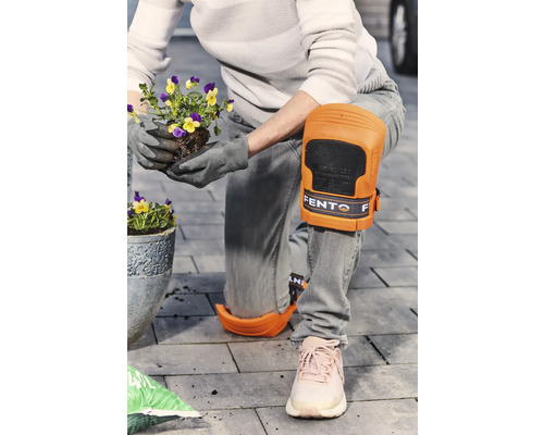 Une personne portant des genouillères plante des fleurs dans le jardin.