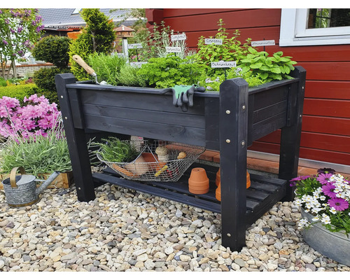 Jardinière sur pieds en bois avec herbes aromatiques, outils de jardinage et espace de rangement dans le jardin.