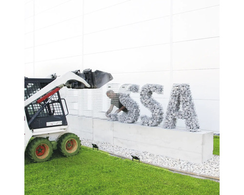 Bau einer Gabionenwand mit Steinen und einem Minibagger zur Unterstützung.