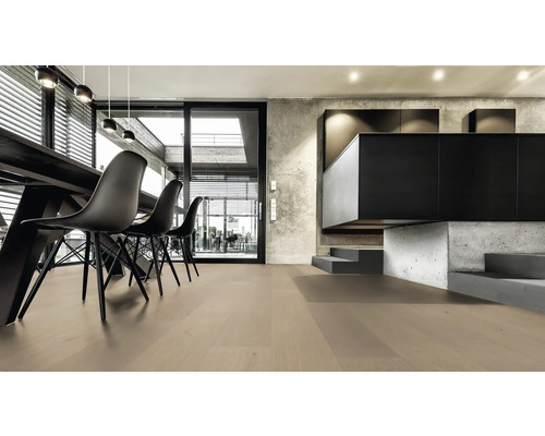 Heller Wohnraum mit Holzboden, Esstisch und schwarzen Stühlen.