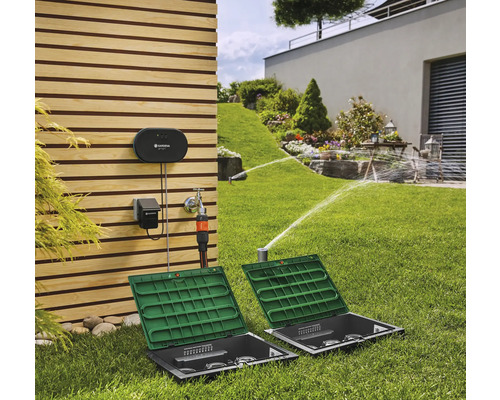 Système d''arrosage Gardena dans le jardin avec arroseurs de gazon et système de commande sur le mur de la maison