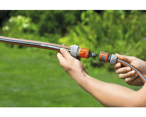 Eine Person verbindet zwei Gartenschläuche mit einem Kupplungsstück.