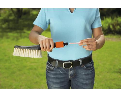 Une femme raccorde une brosse de lavage à un raccord de tuyau.