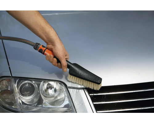 Une personne nettoie une voiture avec une brosse de lavage.