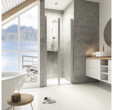 Salle de bains lumineuse avec douche, lavabo et baignoire sous une grande fenêtre donnant sur un lac.