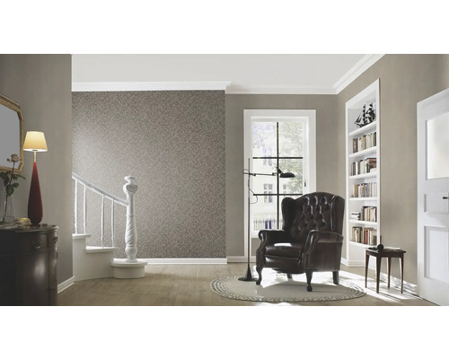 Salon avec papier peint, fauteuil, escalier et éléments décoratifs pour une ambiance chaleureuse