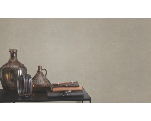 Vases décoratifs en verre et carnets sur une table devant un mur avec du papier peint texturé