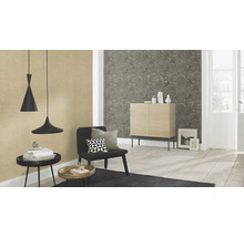 Salon avec suspensions, fauteuil, table et commode devant un papier peint structuré.