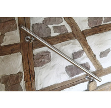 Edelstahl-Handlauf an einer Wand mit Holzrahmen und Steinen