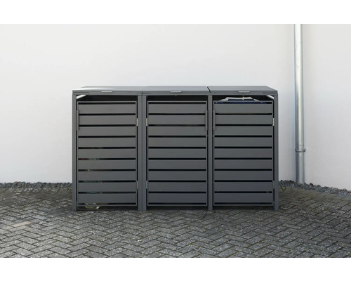 Trois abris poubelles gris avec une structure à lamelles devant un mur blanc.