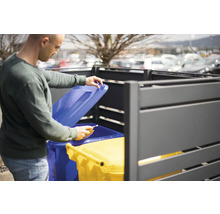 Mann öffnet Mülltonnenbox mit zwei Mülltonnen