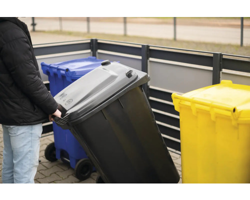 "Person schiebt eine Mülltonne mit Rollen