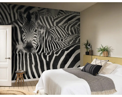 Chambre avec un papier peint photo à motif zébré, un lit et un tabouret en bois.