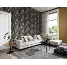 Salon avec un canapé gris, un tapis à motifs et un papier peint à feuilles pour une ambiance chaleureuse