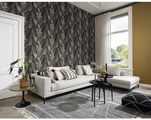 Salon avec un canapé gris, un tapis à motifs et un papier peint à feuilles pour une ambiance chaleureuse