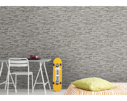 Pièce à vivre avec papier peint imitation pierre, bureau, chaise, skateboard et lit