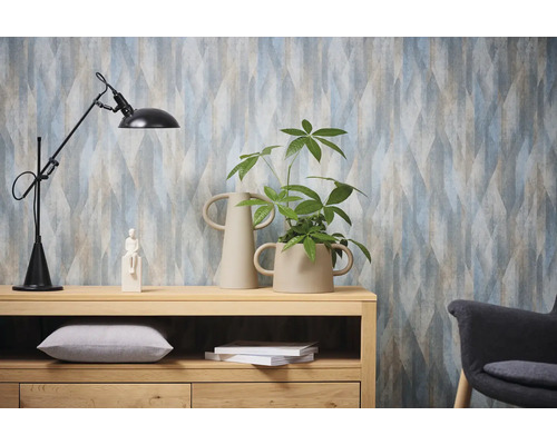 Dekoratives Interieur mit gemusterter Tapete, Stehlampe, Holzkommode und Zimmerpflanze.