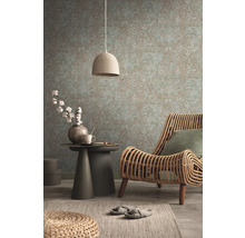 Gemütliches Interieur mit Rattansessel, Beistelltisch, Lampe und gemusterter Tapete