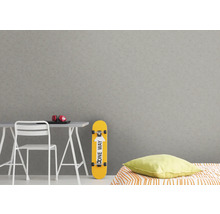 Helles Zimmer mit Schreibtisch, Stuhl, Skateboard und gemusterter Tapete