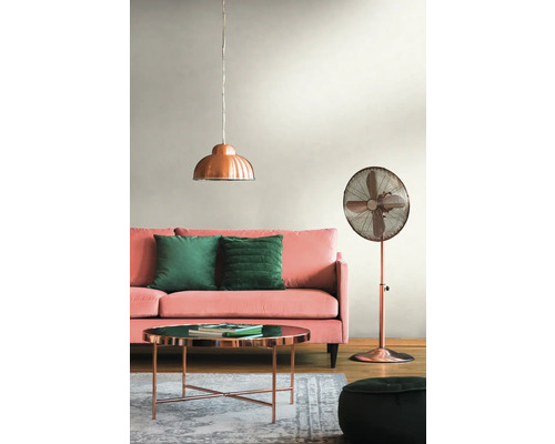 Wohnzimmer mit rosa Sofa, grünen Kissen, kupferfarbenem Tisch, Stehlampe und Pendelleuchte.