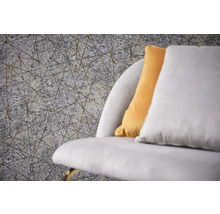 Nahaufnahme einer grauen Strukturtapete mit einem geometrischen Linienmuster neben einem Sofa mit Kissen