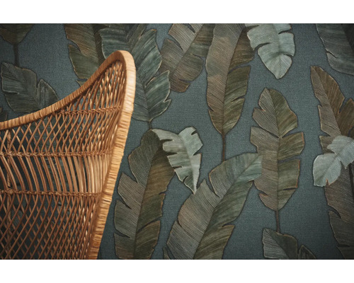 Detailaufnahme einer Tapete mit Blattmuster neben einem Korbweidenstuhl