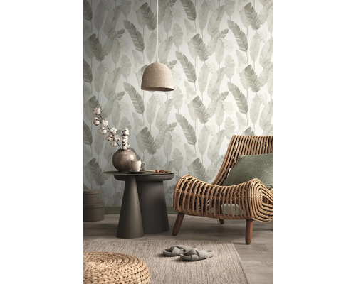 Salon avec papier peint à feuilles, fauteuil en rotin et table d''appoint