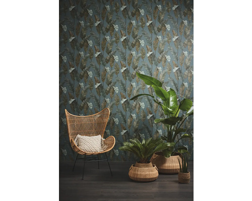 Wohnraum mit Rattan-Sessel, Pflanzen und einer Tapete mit Blättermuster