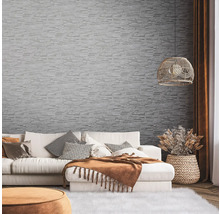 Wohnzimmer mit Sofa, Dekokissen und Wandtapete in Steinoptik.