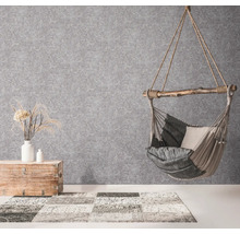 Hängesessel mit Kissen, Holztruhe mit Dekoration und Teppich in einem hellen Raum.