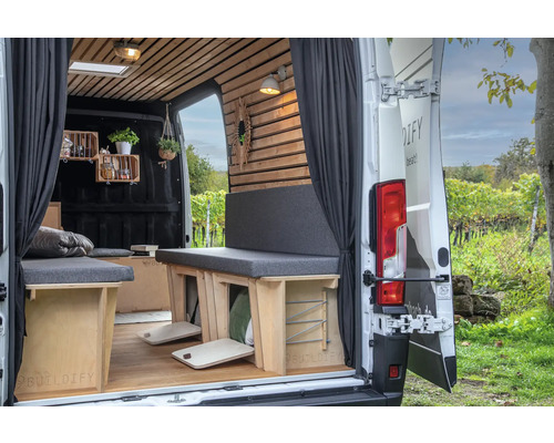 Innenraum eines umgebauten Lieferwagens mit Holzboden, Sitze mit grauen Polstern und Regale