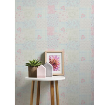 Dekorative Tapete im Patchwork Design mit Blumenmuster hinter einem Tisch mit Dekoration
