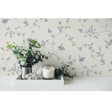 Papier peint décoratif à motifs floraux dans une pièce lumineuse, combiné à une bougie et à des plantes vertes.